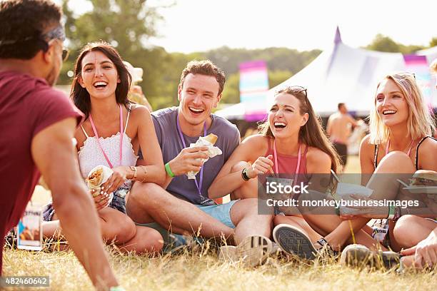 Friends Sitting On Grass And Eating At Music Festival Stock Photo - Download Image Now