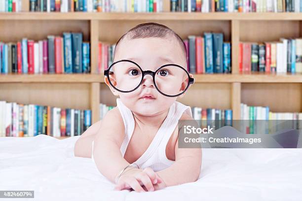 Sweet Baby With Glasses And A Bookcase Background Stock Photo - Download Image Now - Baby - Human Age, Bookshelf, 2015