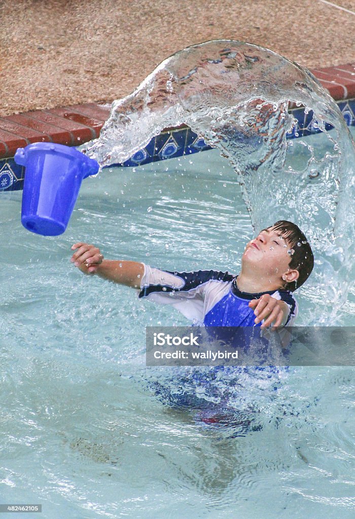 Sensory Water Play vertical orientation of a teenage boy with autism and down's syndrome in a pool outside playing with a bucket of water Sensory Perception Stock Photo