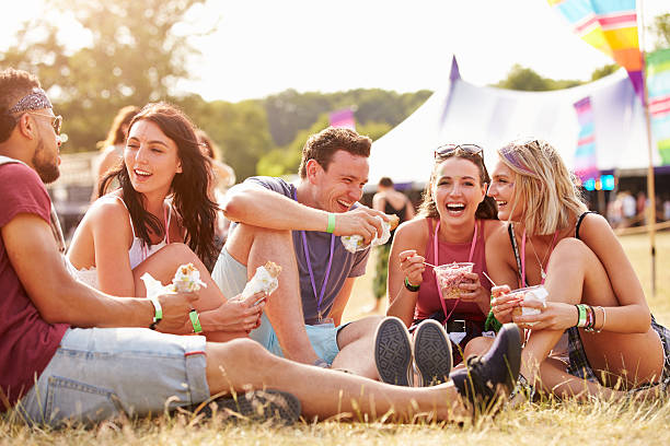 freunde sitzen auf die gras essen im music festival - festival stock-fotos und bilder