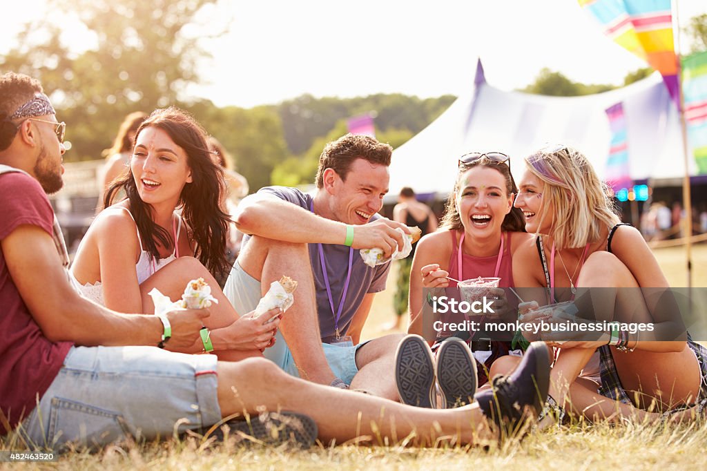 Friends sitting on the grass eating at a music festival Traditional Festival Stock Photo