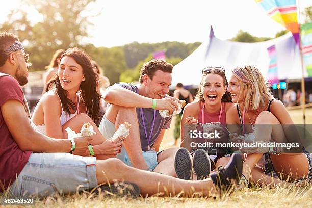 Friends Sitting On The Grass Eating At A Music Festival Stock Photo - Download Image Now