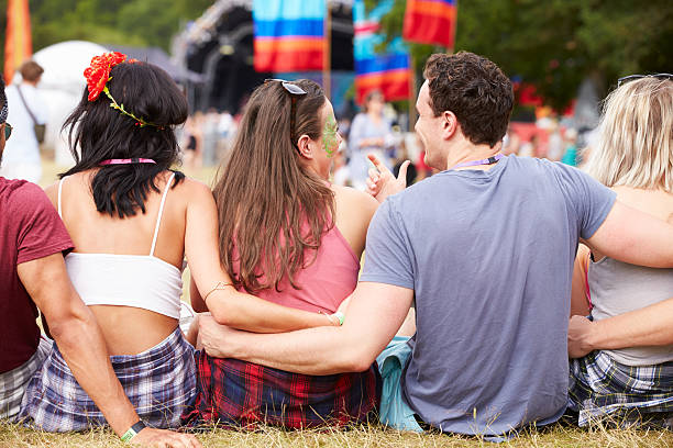 istock Young people sitting outdoors at a music festival, back view 482463676