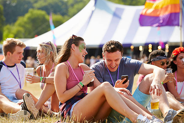 istock Friends sitting on grass using smartphone at music festival 482463762