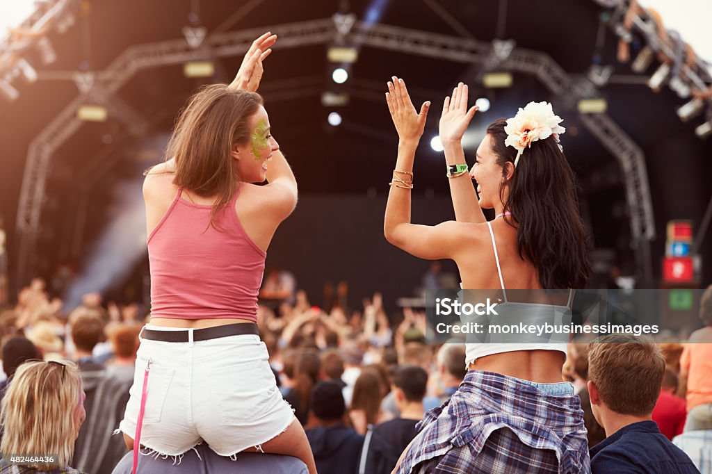 Two girls on shoulders in the crowd at music festival Two girls on shoulders in the crowd at a music festival Traditional Festival Stock Photo