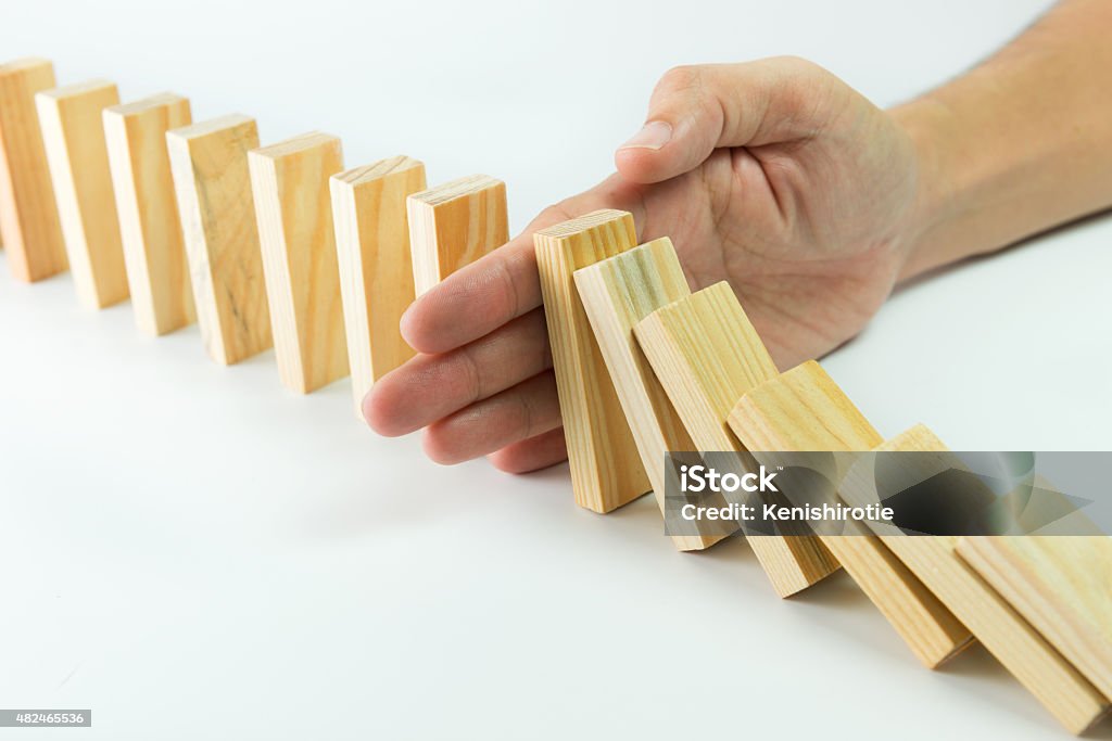 Solution Solution concept with hand stopping wooden blocks from falling in the line of domino Crisis Stock Photo