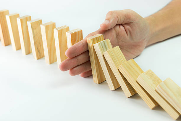 Solution Solution concept with hand stopping wooden blocks from falling in the line of domino withstand stock pictures, royalty-free photos & images
