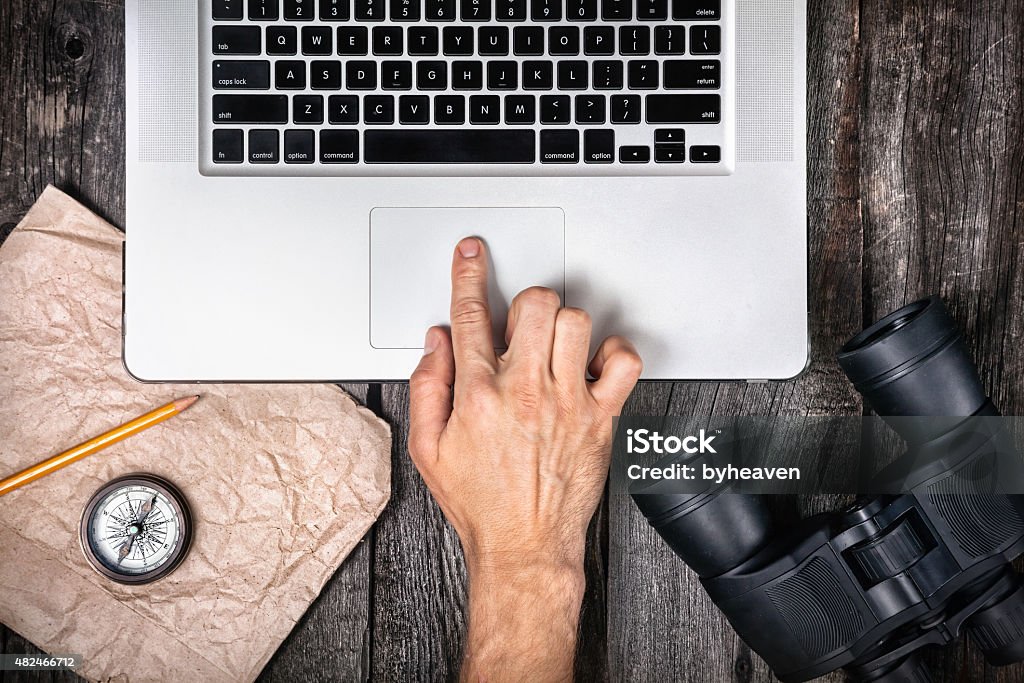 Travel concept Traveler preparing to his trip with laptop, compass and binocular on the wooden background Binoculars Stock Photo