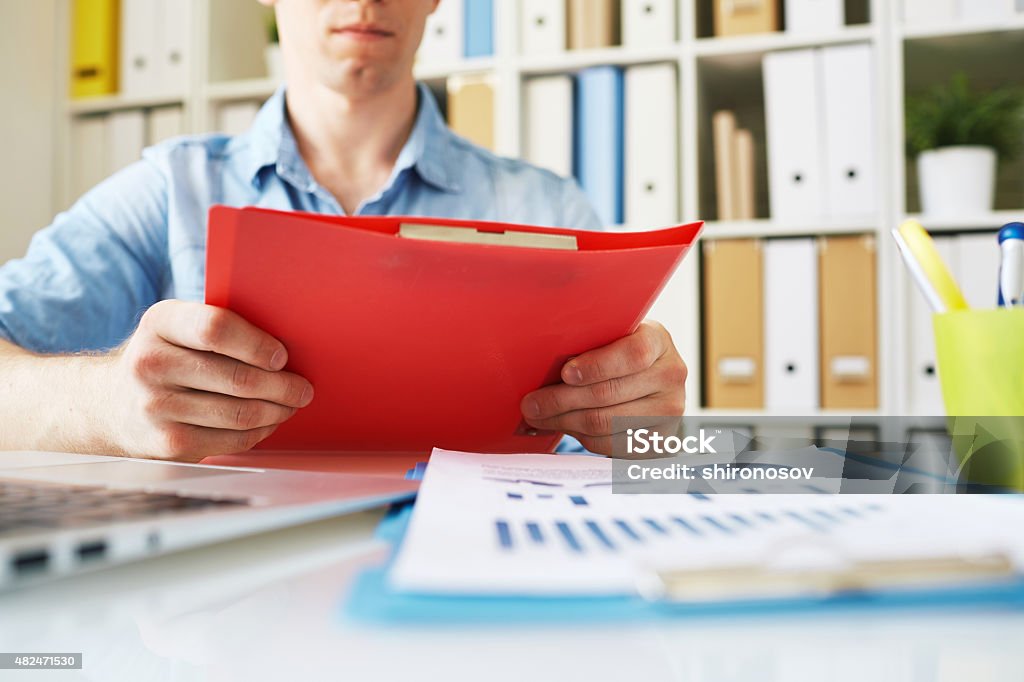 Businessman at work Businessman holding red folder over workplace 2015 Stock Photo