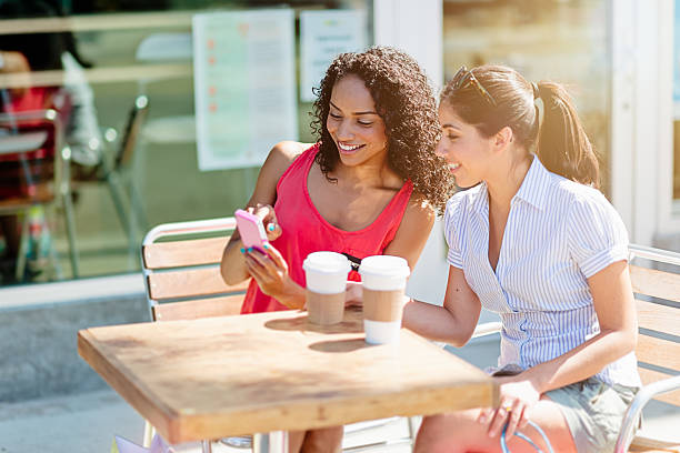istock Two girlfriends surfing on the net in sidewalk cafe 482475230