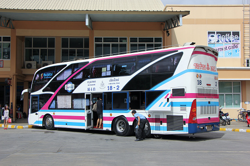 Thai bus at Erawan National Park in Kanchanburi. Bus is parked on parking lot and is connecting par area with city Kanchaburi. In background is a building