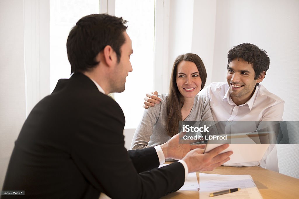Young Couple meeting real-estate agent to buy property, presentation tablet Woman man advisor office  contract house investment computer Digital Display Stock Photo