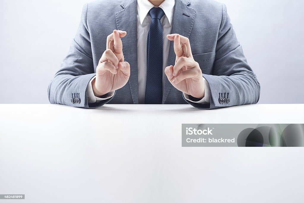 Businessman Double Fingers Crossed Businessman double fingers crossed at the desk. Crossing Stock Photo