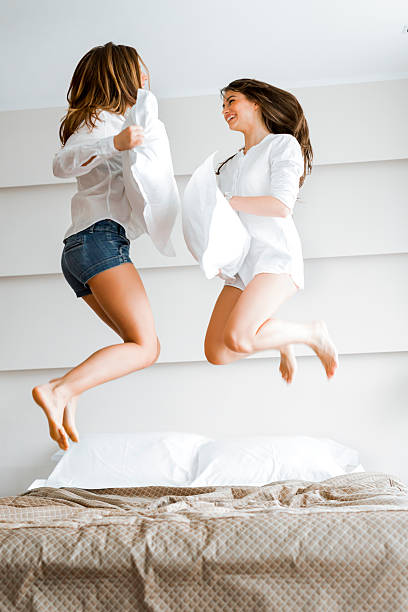 istock Two beautiful women jumping on bed and fighting with pillows 482484060
