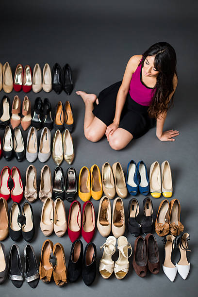 High angle view of a woman sitting near high heels in a store and smiling