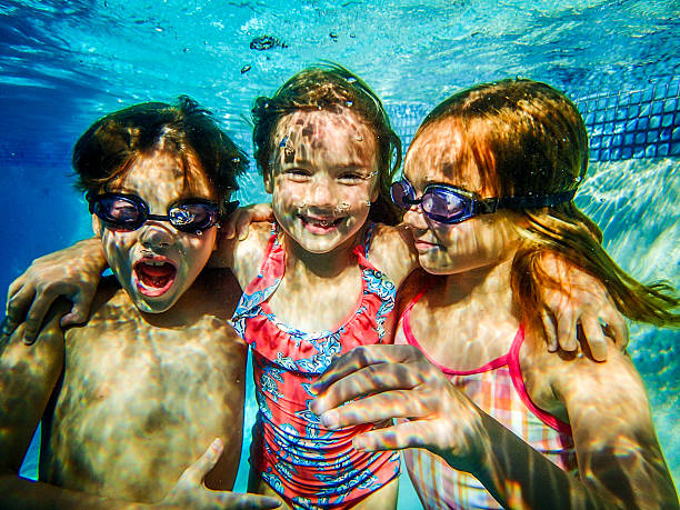 istock Three 3 happy kids in swimming pool underwater 482493127