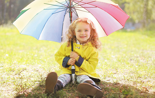 Charming smiling little girl with colorful umbrella autumn