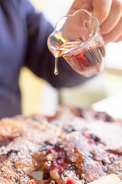 Man's Hand Pours Maple Syrup, Droplet Suspended over Berry Pancakes