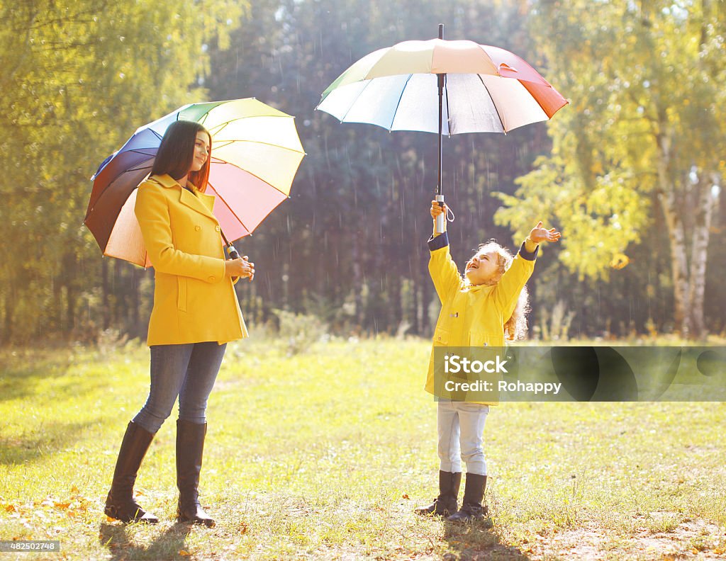 Family with colorful umbrella having fun enjoying weather in aut Family with colorful umbrella having fun enjoying weather in autumn day Mother Stock Photo