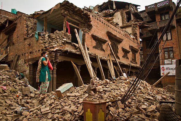 Woman outside her earthquake ruined house in Bhaktapur, Nepal Bhaktapur, Nepal - May 9, 2015: Woman outside her earthquake ruined house in Bhaktapur, Nepal. Earthquake damage on the streets of Bhaktapur. Located 30km east of Kathmandu, the town was once rich with Buddhist and Hindu temples and a popular tourist spot for those visiting Kathmandu, Nepal thamel stock pictures, royalty-free photos & images