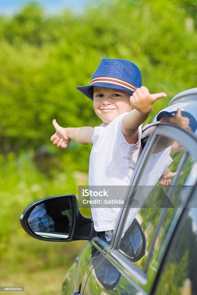 Retrato de menino bonito no carro mostrando os polegares para cima O sinal - Foto de stock de Carro royalty-free