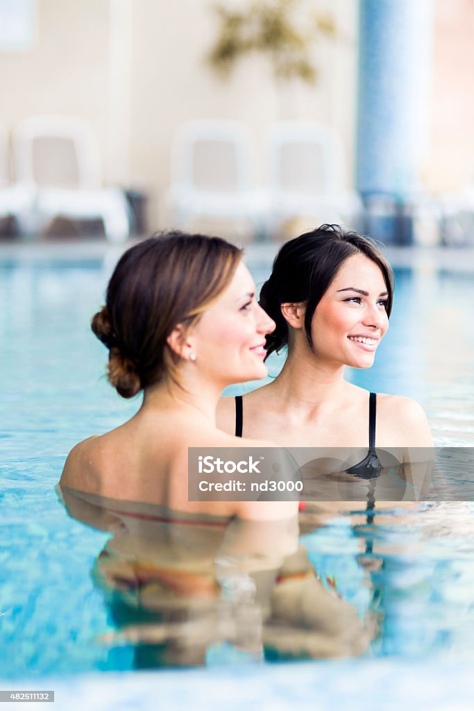 Beautiful young women in a swimming pool Beautiful young women talking and relaxing in a swimming pool 2015 Stock Photo