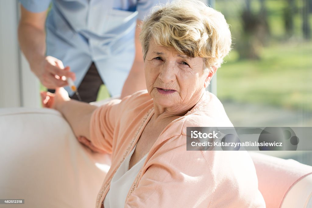 Getting an injection Elderly woman getting an injection from a nuse 2015 Stock Photo