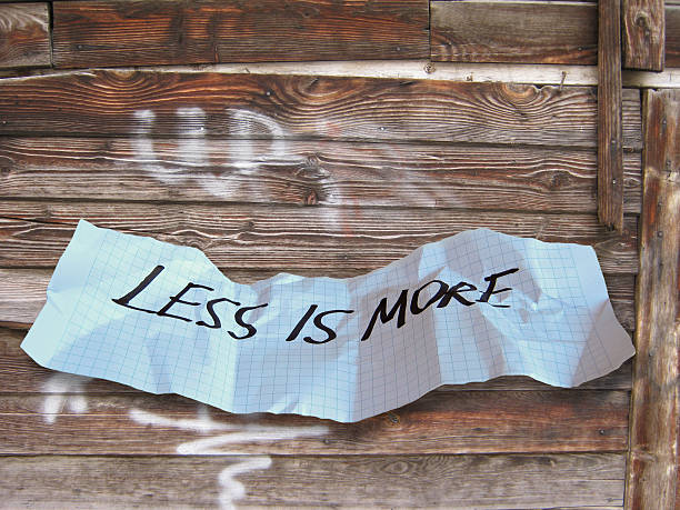 слово «less is more на torned бумага - torned стоковые фото и изображения