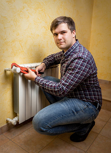 istock young man holding pliers and installing radiator valve 482515466