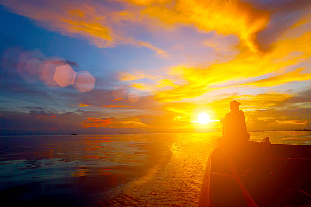 istock Lonely men silhouettes on sunset sky beautiful lagoon 482518807