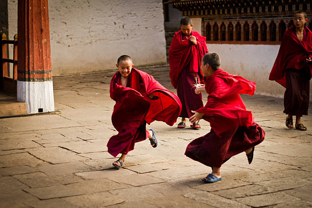Rinpung Dzong Fortress Monastery school for monks, Bhutan Paro, Bhutan - October 28, 2014: Novice Buddhist monks play in the courtyard of The Rinpung Dzong Fortress Monastery school for monks, Paro, Bhutan bhutan stock pictures, royalty-free photos & images