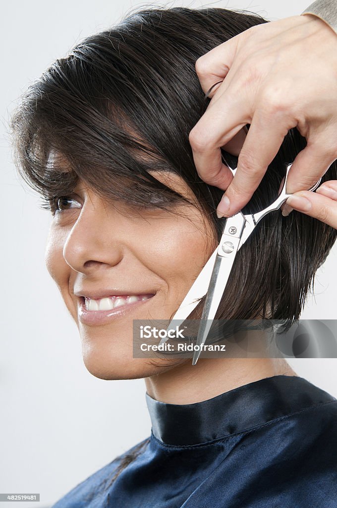 Cutting hair Beautiful happy young woman cutting hair at the hairdresser salon. Cutting Stock Photo