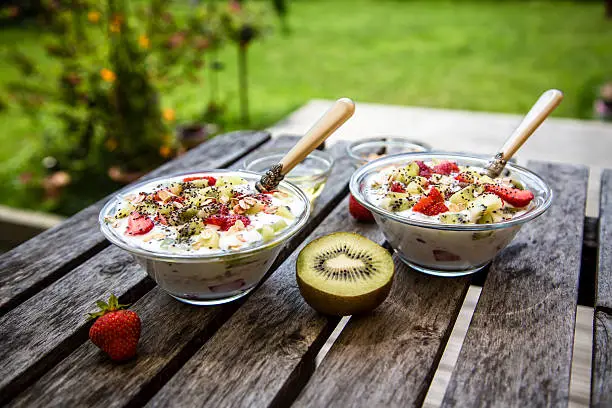 Strawberry-kiwi-yogurt with granola, chia-seeds and agave-syrup in glass bowls