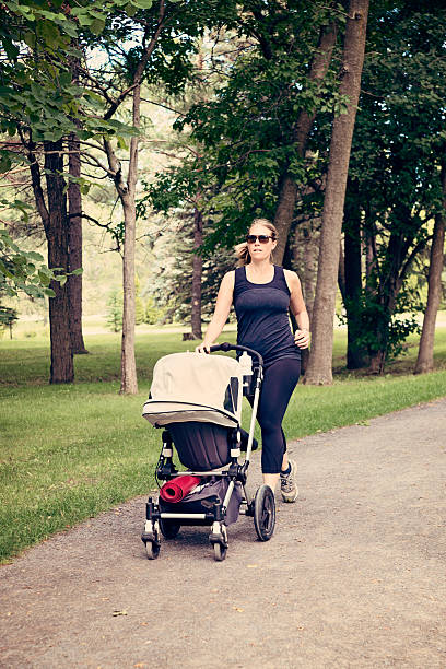 istock New mother jogging with stroller in public park. 482520224