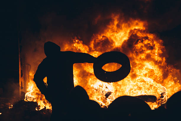 uomo getta all'interno di un pneumatico fuoco - riot foto e immagini stock