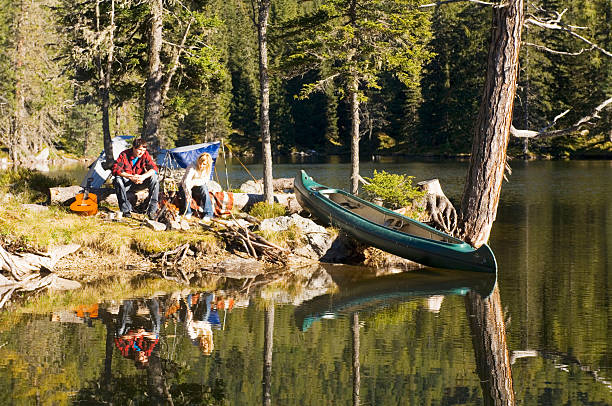 A red canoe on a very calm lake in the middle of fall.