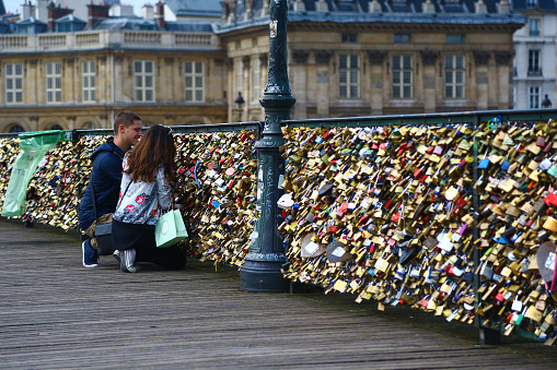 Paris, France - June 25, 2013: two lovers lock their padlock on Pont des Arts.