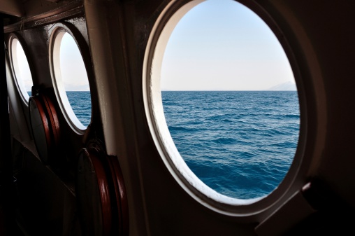 Open boat porthole with ocean view close up