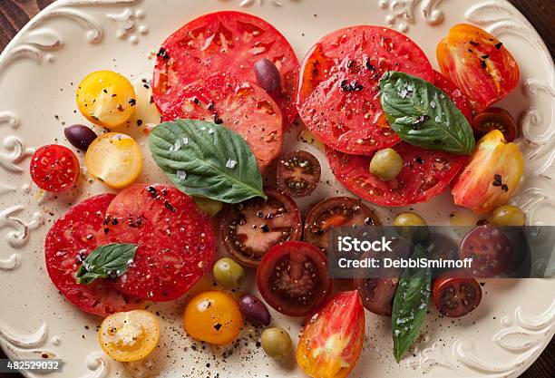 Sliced Heirloom Tomatoes And Olives On A Plate Stock Photo - Download Image Now - Heirloom Tomato, Freshness, Red