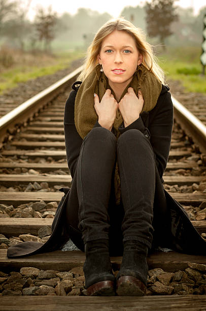 istock Young blond lady sitting on the train tracks 482531929