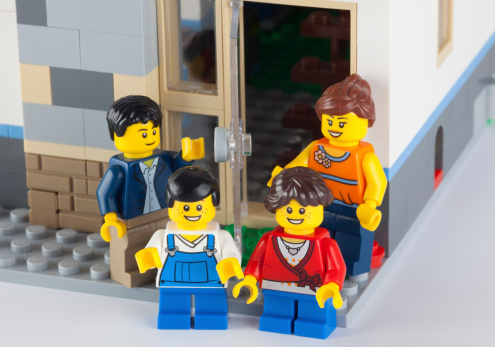 Tambov, Russian Federation - January 12, 2014: Happy LEGO family standing near his home. There are minifigures of mom, dad, son and daughter. Studio shot.