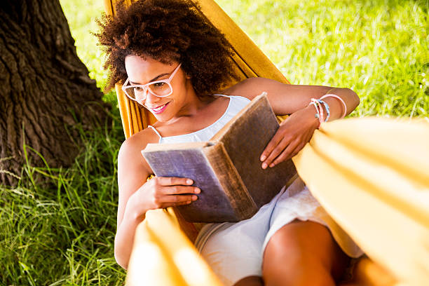 istock woman holding book in a hammock 482536709