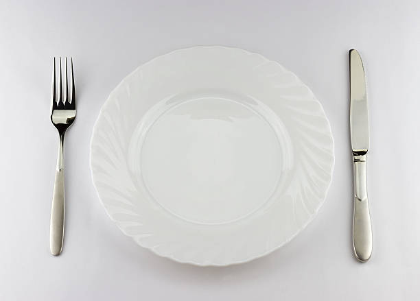 istock Top view of white plate with silver fork and knife 482541566