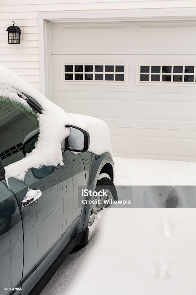 Winter Snow Car and Garage Door A generic snow-covered car parked in a generic residential driveway in front of a closed generic garage door. Driveway Stock Photo