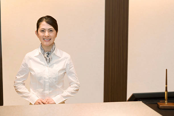 Smiling female office worker standing still in front desk stock photo