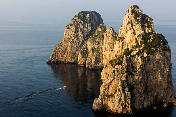 A huge rock and a motorboat on the sea in the island of Patmos, Greece in summer time