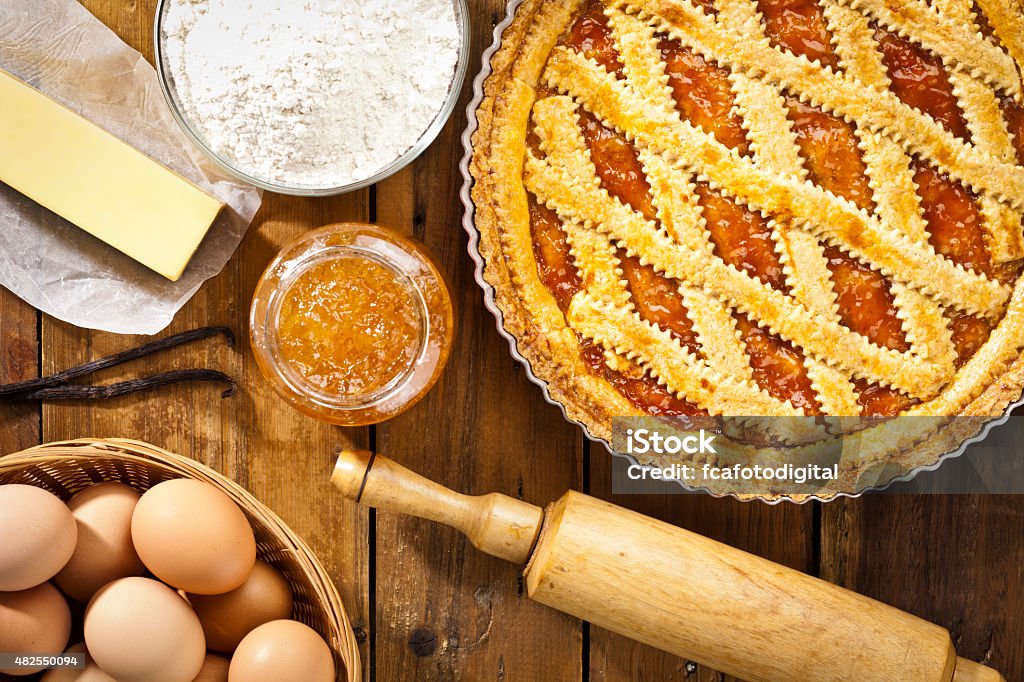Homemade italian crostata with ingredients shot directly above Homemade italian crostata in a round baking tray with ingredients shot directly above on rustic wood table. Predominant colors: brown and yellow. DSRL studio photo taken with Canon EOS 5D Mk II and EF 100mm f/2.8L Macro IS USM Tart - Dessert Stock Photo