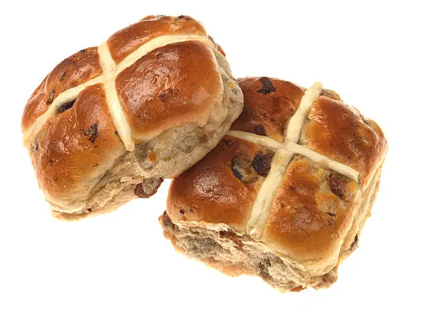 Two fresh lightly spiced hot cross buns with dried fruit, eaten at Easter Time, isolated against a white background, clipping path, cut out