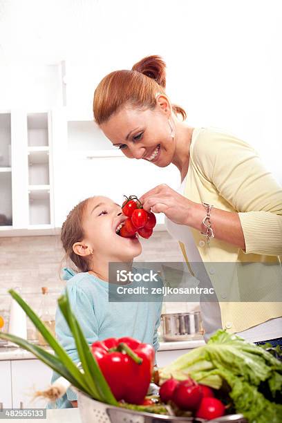 Bambina Mangiare Di Pomodoro In Cucina - Fotografie stock e altre immagini di Adulto - Adulto, Alimentazione sana, Allegro