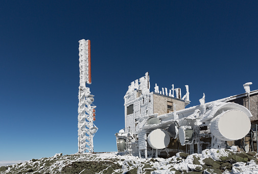 Frozen tower and communication equipment at summit of Mount Washington, Usa on a nice day with a clear blue sky without a cloud.